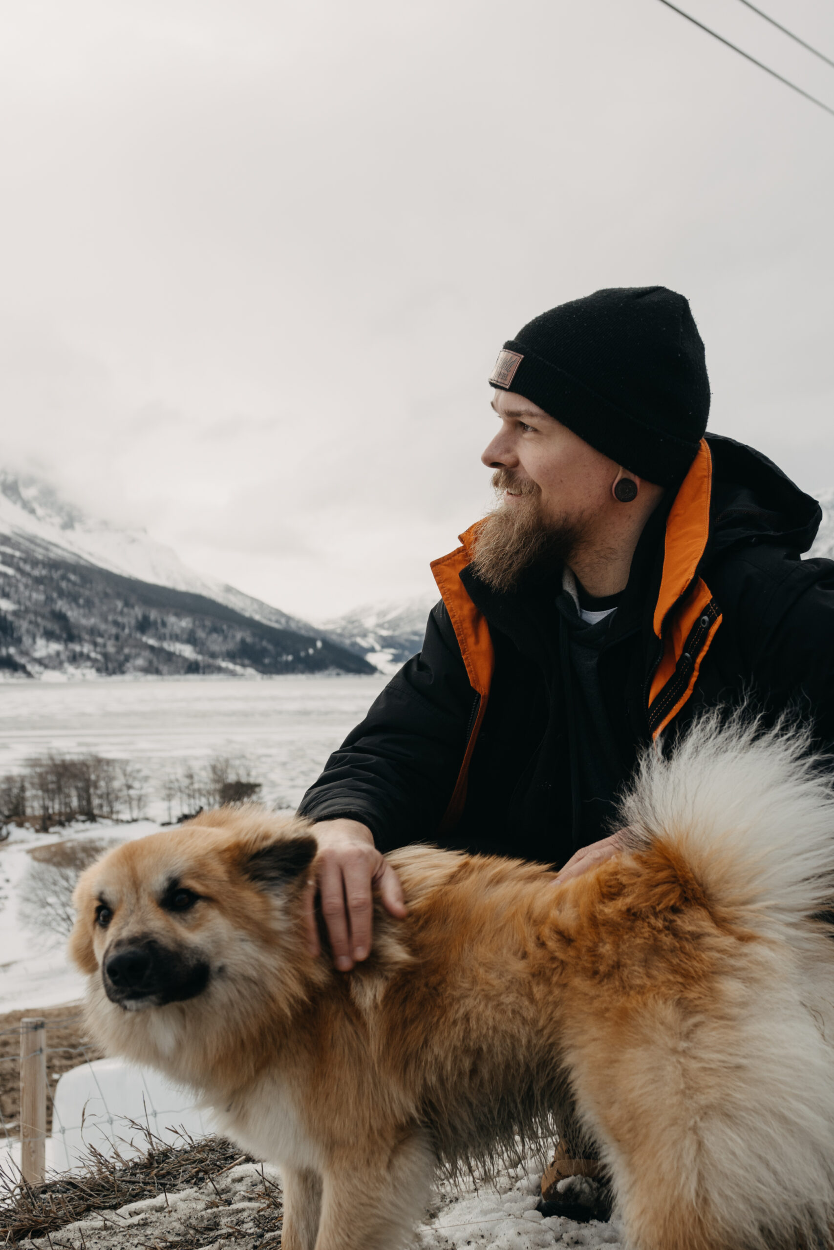 Henry mit Hund in Norwegen. Es sind Berge und ein gefrorener See im Hintergrund zu sehen.